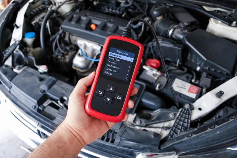 Tester portabil ținut lângă motor pentru citirea parametrilor OBD2