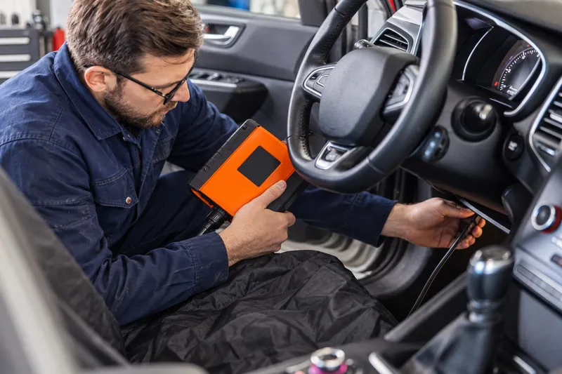 Tehnician care conectează cablul testerului la mufa OBD2 de sub bord